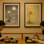 和食レストランの壁に飾られた2枚の写意画と、食事を楽しむ男女の姿。月夜を描いたモノクロの花と、朝日の下に咲く色彩豊かな花の対比が印象的。